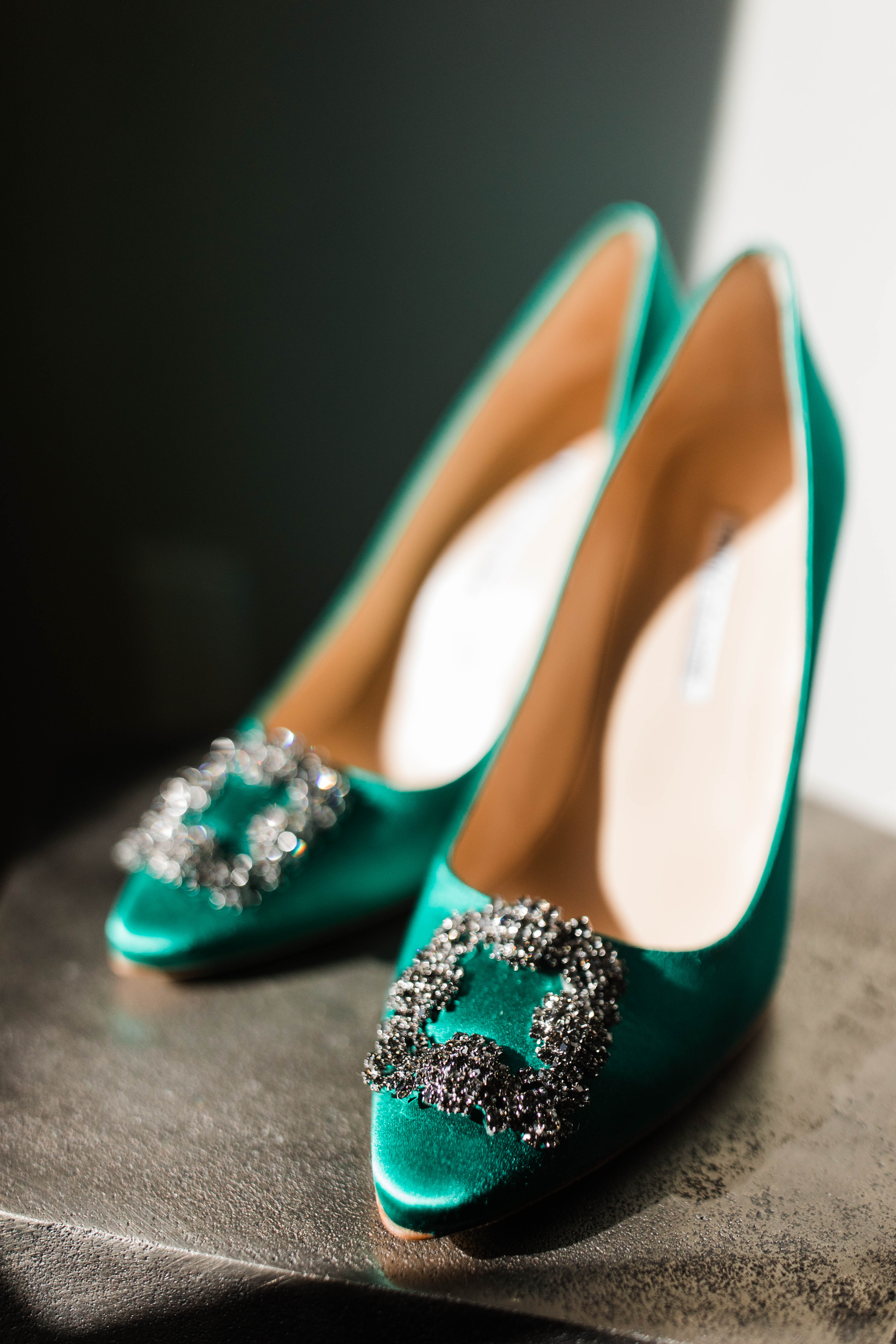 A photo of emerald green shoes with a rhinestone buckle. 