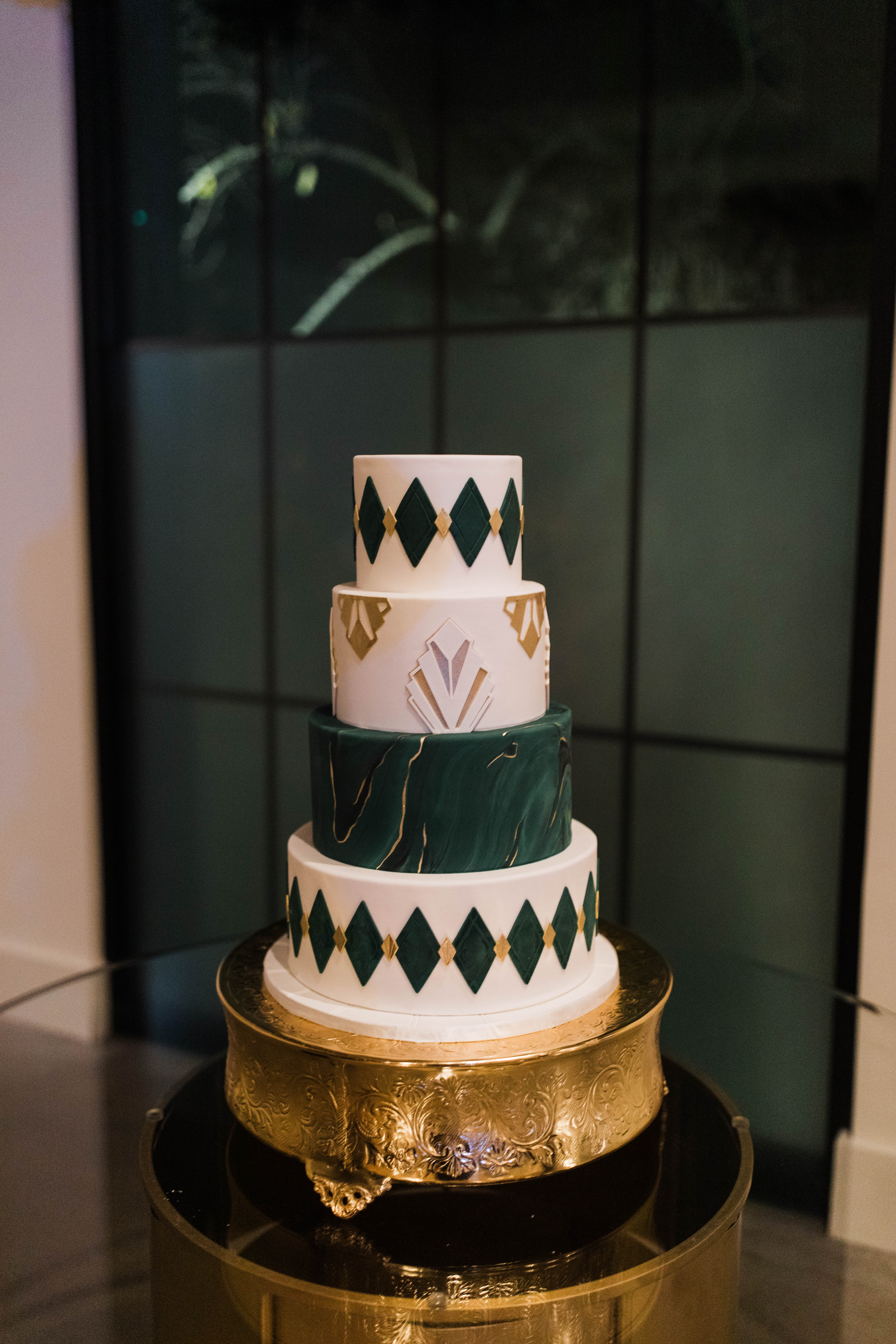 A photos of a 4 tier wedding cake with a green and gold art deco design